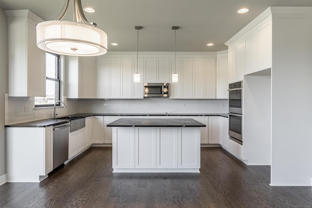 kitchen featuring a sink, dark wood-type flooring, appliances with stainless steel finishes, white cabinetry, and dark countertops