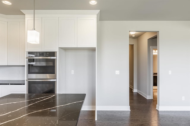 kitchen featuring baseboards, double oven, dark wood-style floors, and white cabinetry