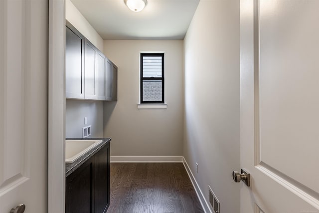 washroom with hookup for a washing machine, visible vents, baseboards, dark wood finished floors, and cabinet space