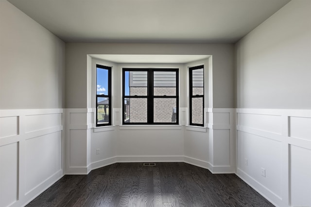 unfurnished room featuring dark wood-style floors and wainscoting