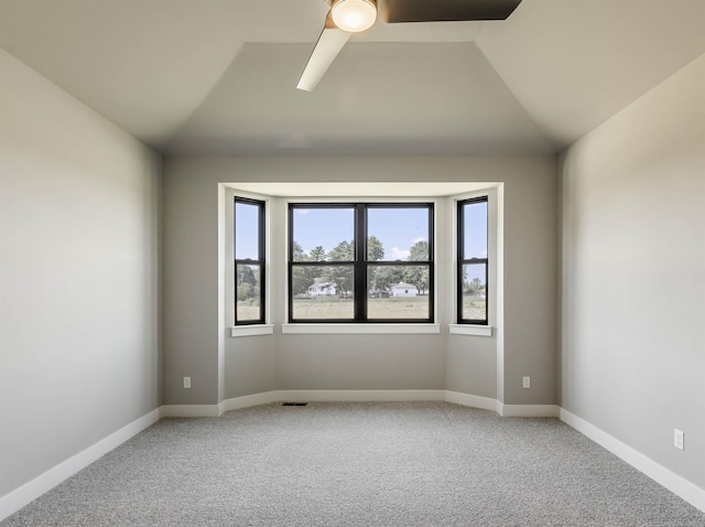 empty room with vaulted ceiling, carpet flooring, baseboards, and ceiling fan