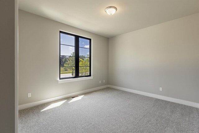 carpeted spare room featuring visible vents and baseboards