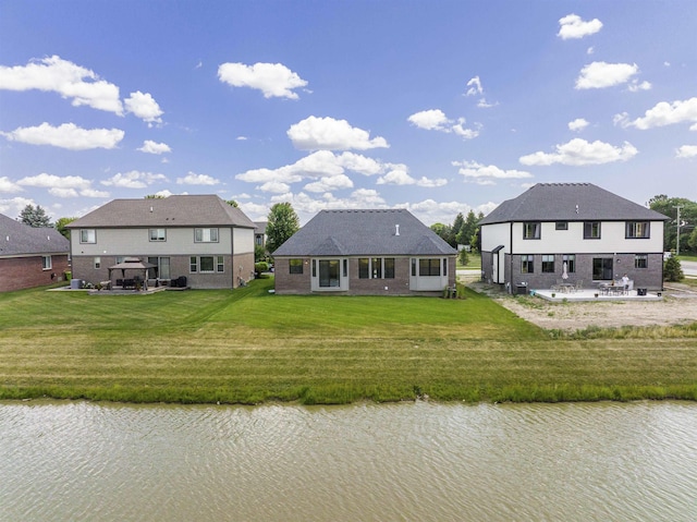 back of house with a patio area, a lawn, and a water view