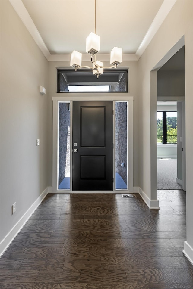 foyer entrance featuring a notable chandelier, dark wood-type flooring, and baseboards