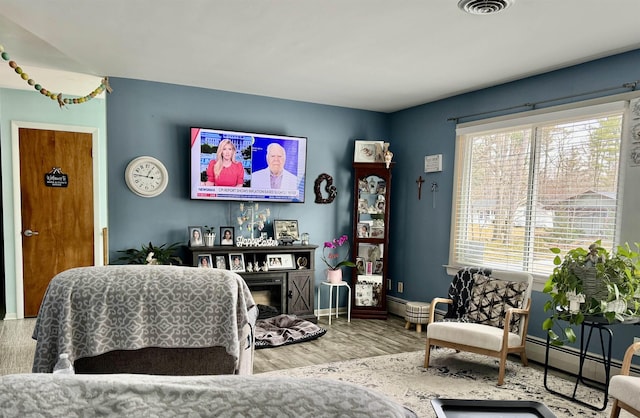 living area featuring visible vents, baseboards, a healthy amount of sunlight, and wood finished floors