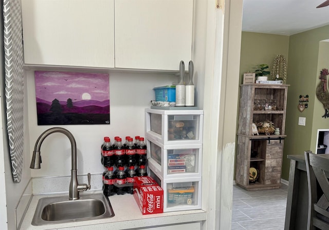 interior details featuring a sink, white cabinets, and light countertops