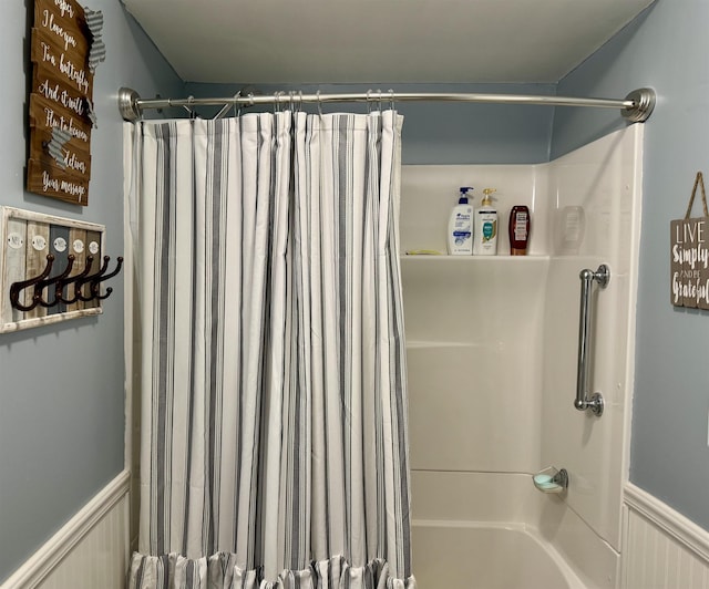 bathroom featuring shower / bath combo and a wainscoted wall