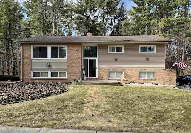 bi-level home with a front lawn, brick siding, and a chimney