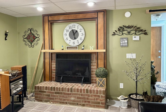 living area with a fireplace, baseboards, and a paneled ceiling