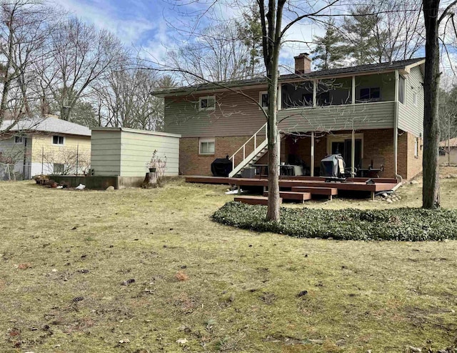 back of house featuring a deck, a yard, brick siding, and a chimney