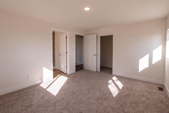 unfurnished bedroom featuring visible vents, light colored carpet, and baseboards