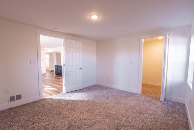 empty room with visible vents, light carpet, and baseboards