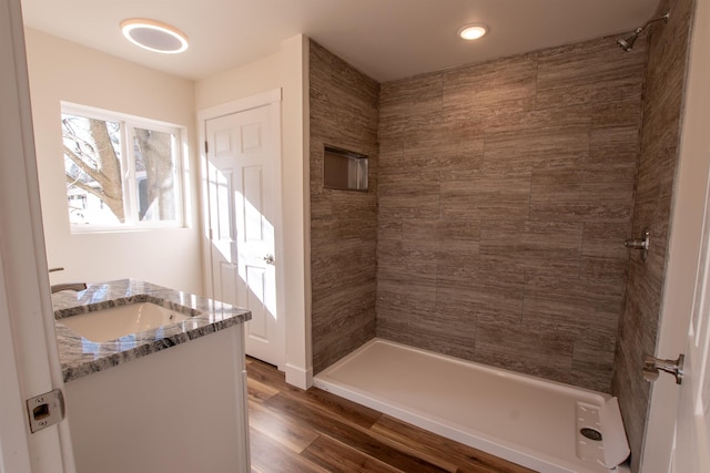 full bath featuring a sink, tiled shower, and wood finished floors