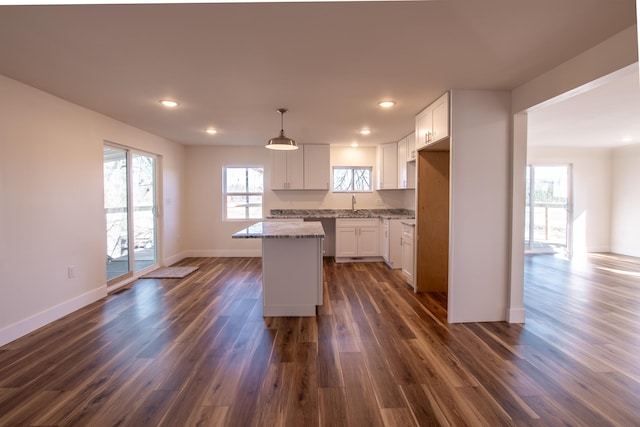 kitchen with dark wood finished floors, white cabinets, a center island, and baseboards