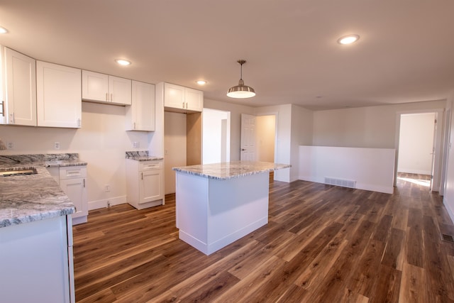 kitchen featuring white cabinetry, light stone countertops, visible vents, and dark wood-style flooring