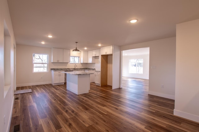 kitchen featuring a sink, dark wood-type flooring, a center island, and white cabinetry