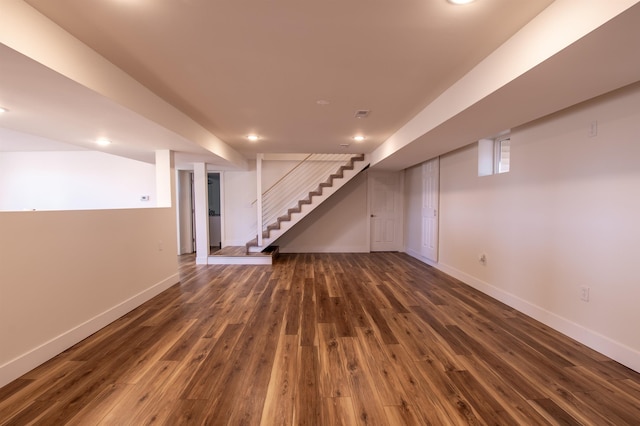 finished basement with stairs, recessed lighting, dark wood-style floors, and baseboards