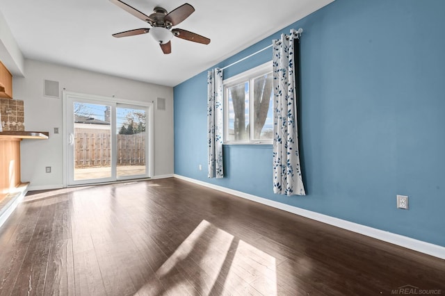 empty room with visible vents, a ceiling fan, baseboards, and wood finished floors