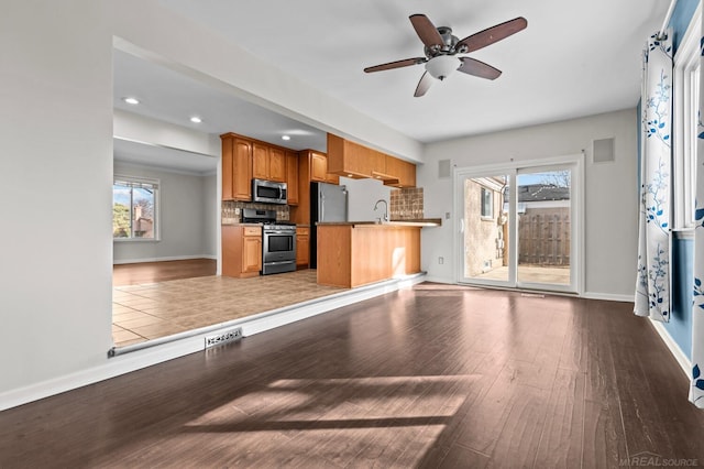 kitchen with backsplash, ceiling fan, brown cabinets, appliances with stainless steel finishes, and wood finished floors