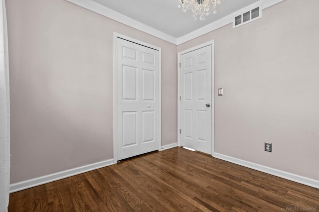 unfurnished bedroom with visible vents, baseboards, dark wood-style floors, and a chandelier