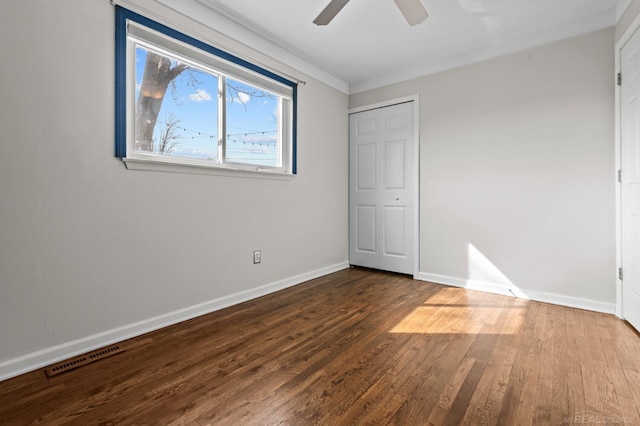 unfurnished bedroom with visible vents, a ceiling fan, baseboards, and hardwood / wood-style flooring