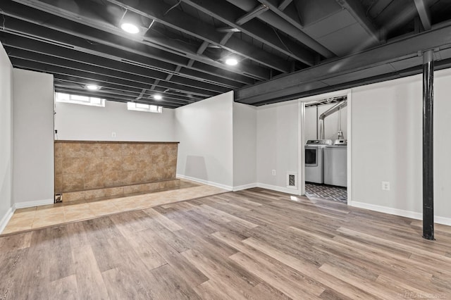 basement with baseboards, wood finished floors, and washing machine and dryer