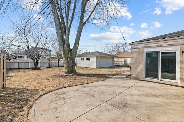 view of yard featuring an outdoor structure, fence, a detached garage, and a patio