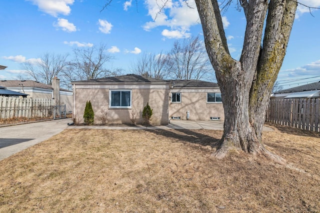 back of property with a yard, fence, and brick siding