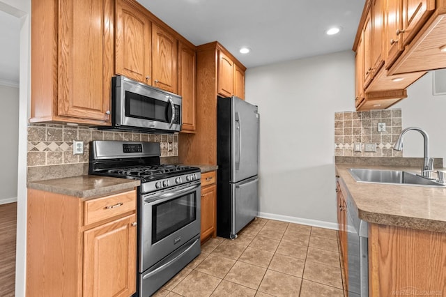 kitchen with tasteful backsplash, baseboards, appliances with stainless steel finishes, light tile patterned flooring, and a sink