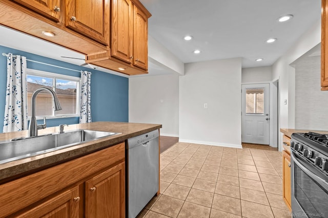 kitchen with light tile patterned floors, recessed lighting, a sink, stainless steel appliances, and dark countertops