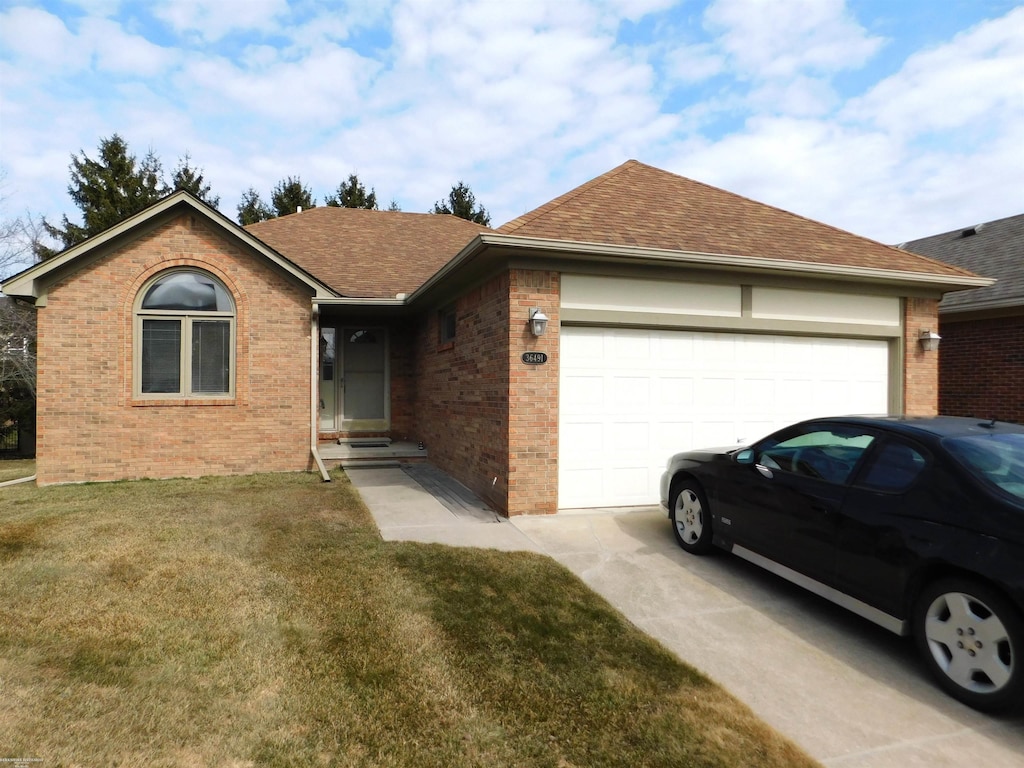 ranch-style home with roof with shingles, concrete driveway, a front yard, an attached garage, and brick siding