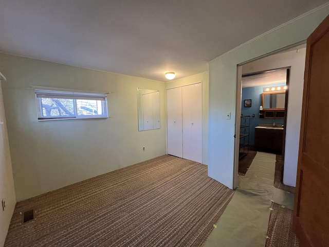 unfurnished bedroom with a closet, visible vents, carpet, and a sink