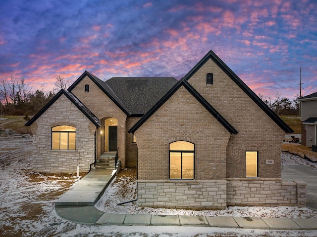 french country style house featuring brick siding and stone siding