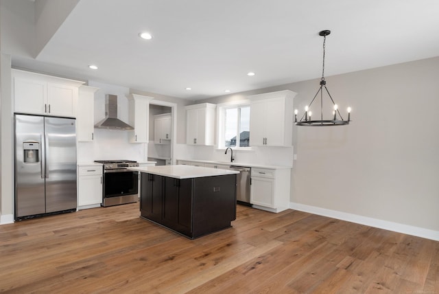 kitchen featuring a chandelier, light countertops, appliances with stainless steel finishes, white cabinetry, and wall chimney exhaust hood