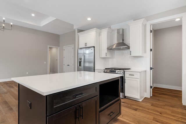 kitchen with stainless steel appliances, white cabinetry, tasteful backsplash, and wall chimney range hood