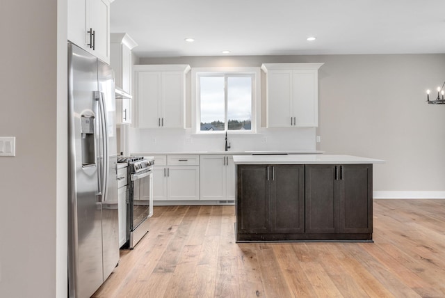 kitchen with light wood-type flooring, appliances with stainless steel finishes, white cabinets, and light countertops