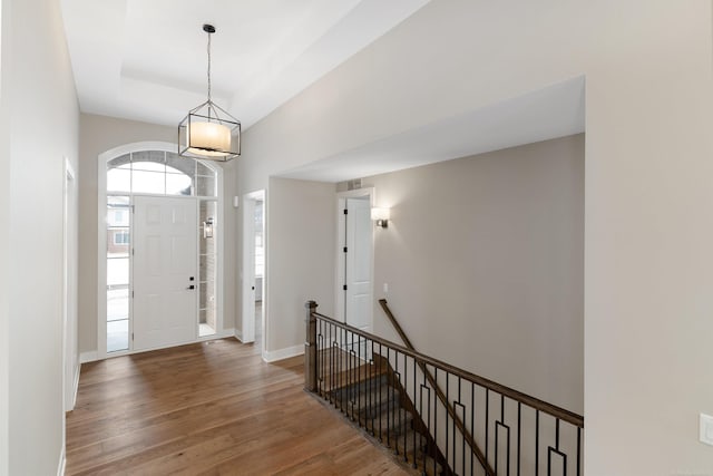 entryway featuring a raised ceiling, baseboards, and wood finished floors