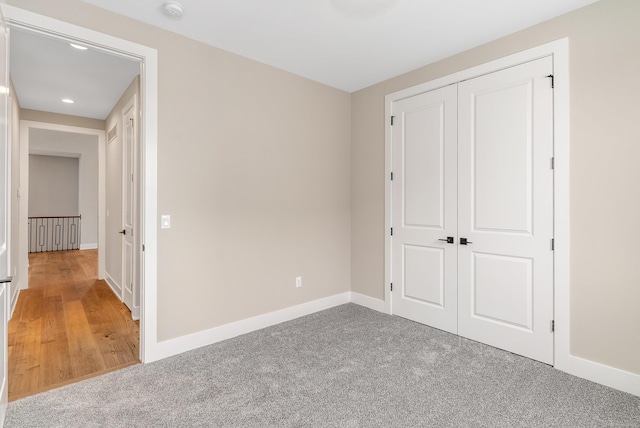 unfurnished bedroom with baseboards, a closet, and light carpet