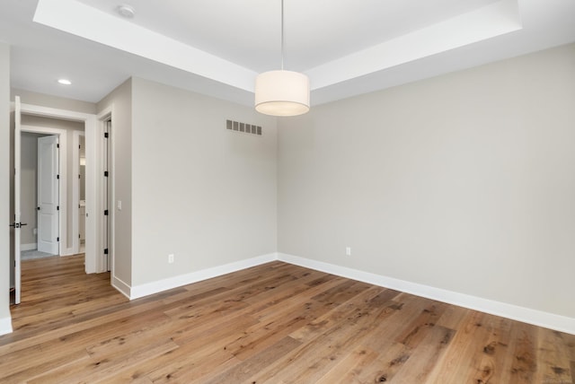 unfurnished room with visible vents, a raised ceiling, and baseboards