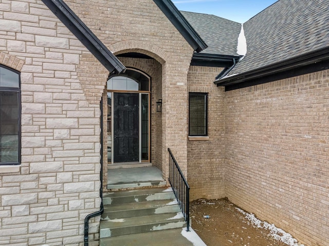 entrance to property with brick siding and roof with shingles