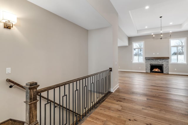 interior space with baseboards, a chandelier, a tray ceiling, recessed lighting, and wood finished floors