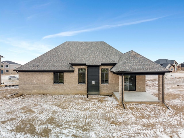 rear view of property with a patio, brick siding, and a shingled roof