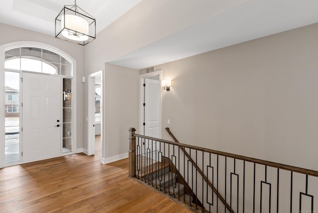 entrance foyer with visible vents, wood finished floors, baseboards, and a chandelier