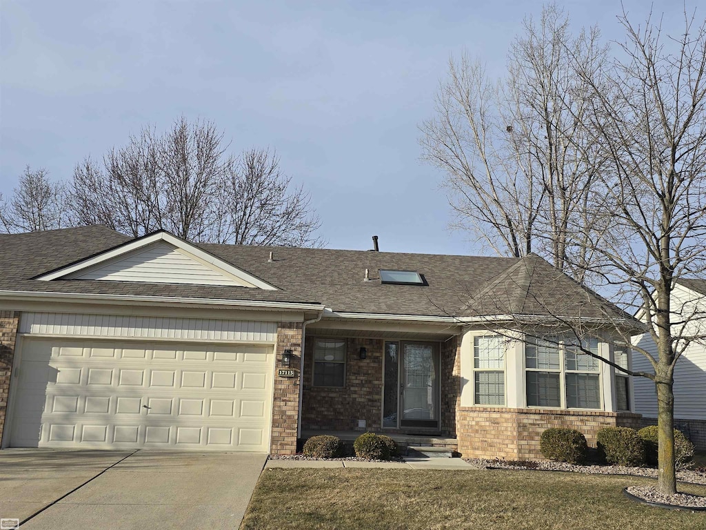 single story home with concrete driveway, an attached garage, brick siding, and a shingled roof