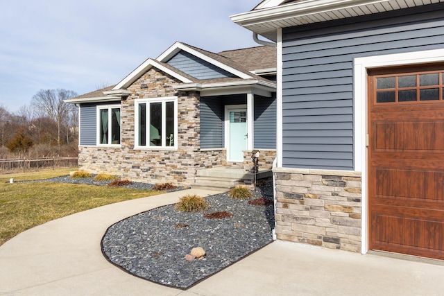 property entrance featuring a garage and stone siding