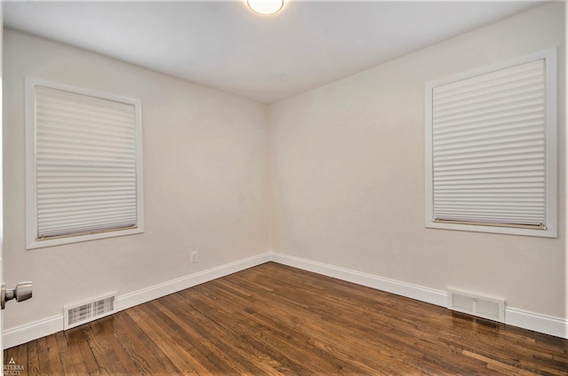 spare room featuring visible vents, baseboards, and dark wood-style flooring