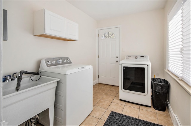 laundry area with light tile patterned floors, cabinet space, independent washer and dryer, and a sink