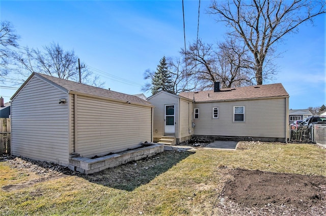 back of property featuring a yard, fence, a chimney, and entry steps