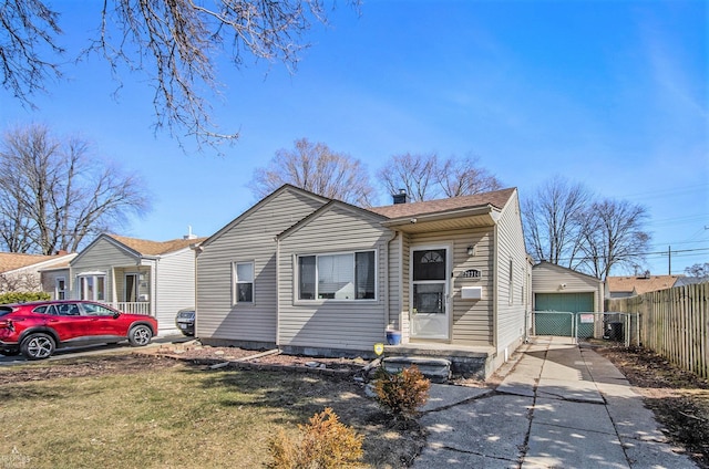 bungalow-style house featuring fence, concrete driveway, a front yard, a garage, and a chimney