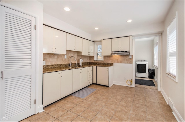 kitchen with under cabinet range hood, a sink, washer / clothes dryer, tasteful backsplash, and white cabinets